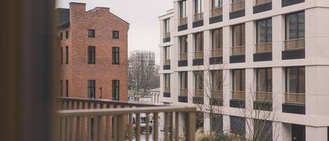 A view of a modern building with a brick facade and a white building with balconies.