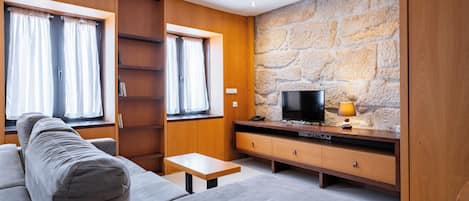En moderne stue med sofa, tv og stenvæg.