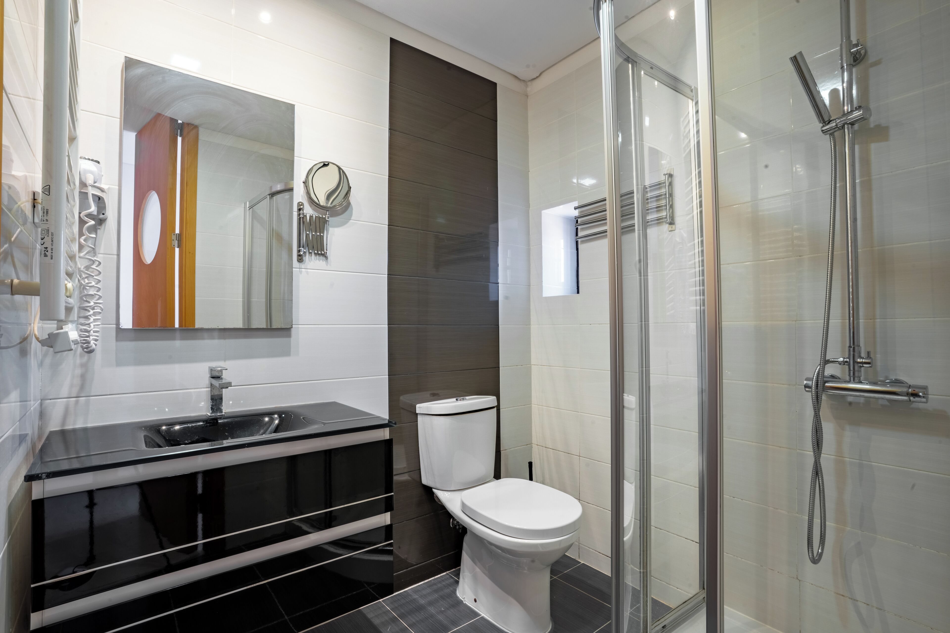 A modern bathroom with a glass shower enclosure, a black vanity with a sink, and a toilet.