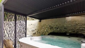 Un área de hidromasaje con pared de piedra y valla metálica.