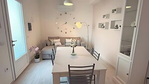 A modern dining area with a white table, black chairs, and a pendant light.