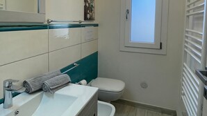 A modern bathroom with a white sink, a toilet, and a window.