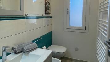 Een moderne badkamer met een wit wastafelmeubel, toilet en raam.