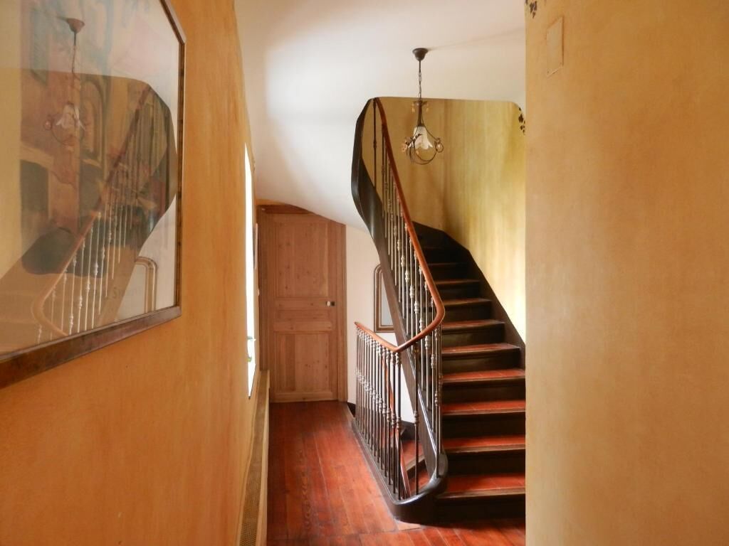 A wooden staircase with a metal railing, a wooden door, and a light fixture.