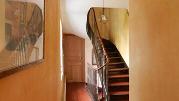 A wooden staircase with a metal railing, a wooden door, and a light fixture.