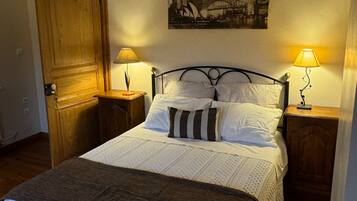 Ein gemütliches Schlafzimmer mit einem Bett, zwei Nachttischen, einer Holztür und einem Stadtbild an der Wand.