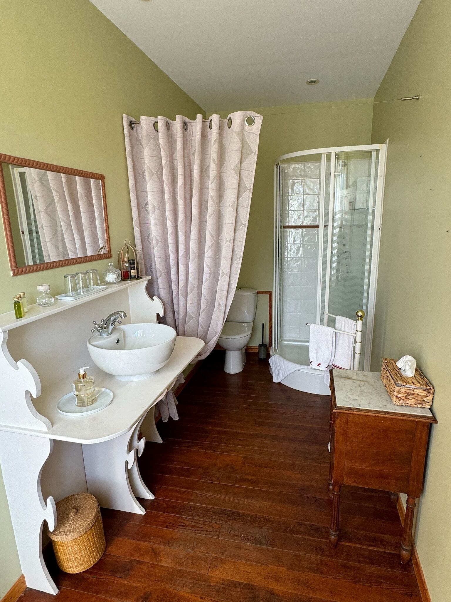 Une salle de bain avec un meuble-lavabo blanc, deux vasques, un miroir et un rideau de douche.