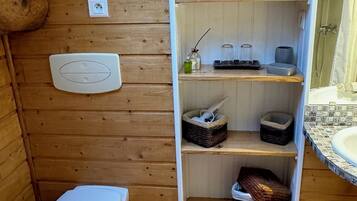Un baño de madera con tragaluz, inodoro, estantes con cestas y zona de ducha.