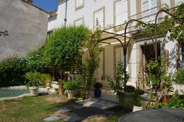A courtyard with a pool, potted plants, and a pergola. - Le Patio des Senteurs (Verzeille)