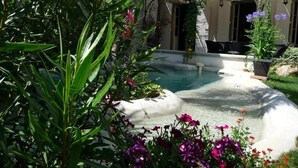 Un cortile con piscina, circondato da vegetazione rigogliosa e piante fiorite.