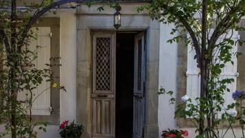 Un edificio in pietra con una porta in legno, piante in vaso e un arco in metallo.