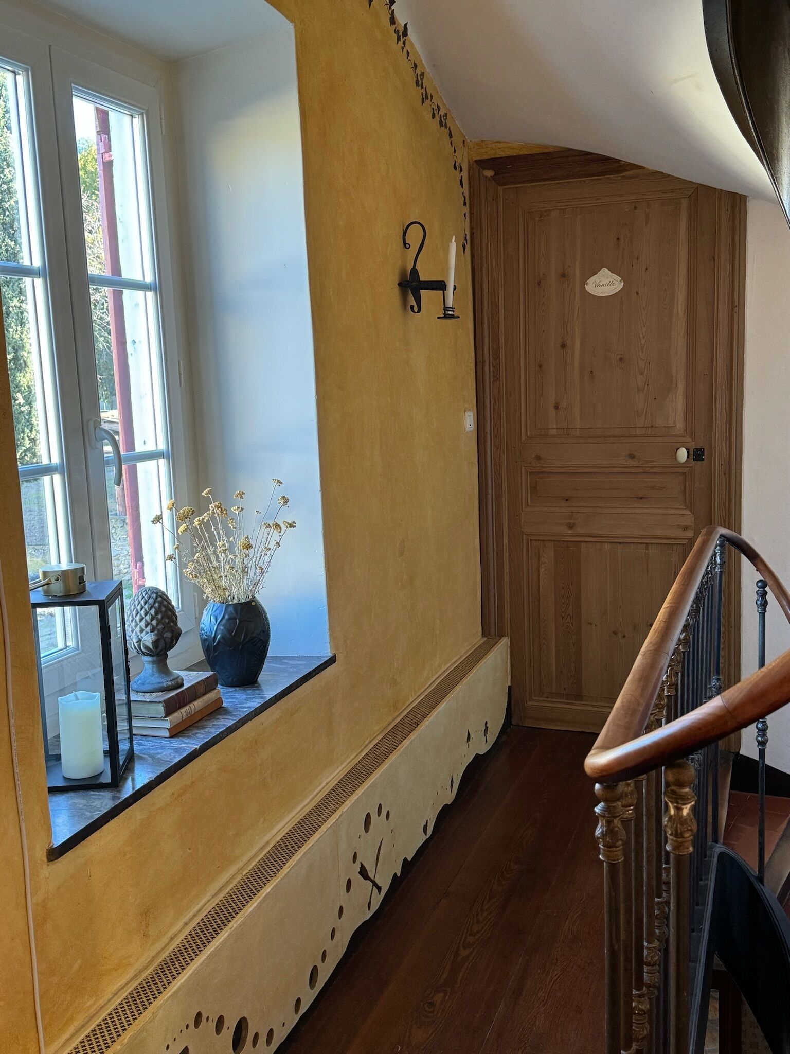 A staircase with a wooden handrail leading to a door labeled "Vanilla."