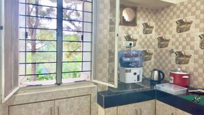 Una cucina con una finestra, un dispenser d'acqua, un bollitore e un contenitore rosso.