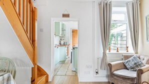 A staircase leading to a kitchen with light green cabinets, a wooden floor, and a view of the outside through a window with curtains. - Laurel Cottage Lincoln, historical character cottage 5 minutes walk to Bailgate (Lincoln)