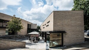 Un bâtiment moderne avec une façade vitrée et un espace extérieur aménagé pour les clients.