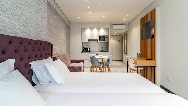A modern hotel room with a large bed, a dining area, and a kitchenette. - Smartr Porto Gaia & Spa (Vila Nova de Gaia)