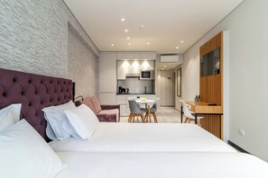 Une chambre d’hôtel moderne dotée d’un grand lit, d’un coin repas et d’une kitchenette.