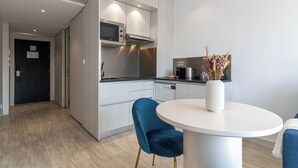 A modern kitchen with a microwave, stove, and dishwasher. There is a dining table with a vase of dried flowers. - Smartr Porto Gaia & Spa (Vila Nova de Gaia)