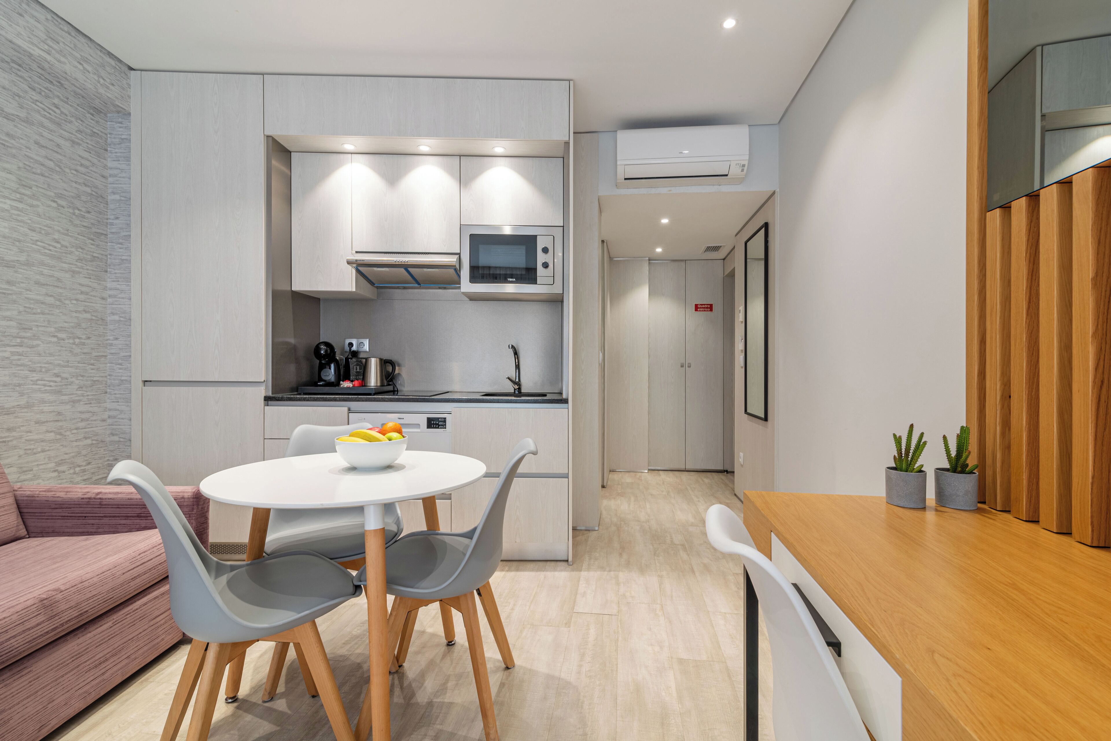 A modern kitchen with a microwave, sink, and dining area with chairs and a table.
