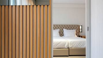 Un dormitorio moderno con una cama grande, un separador de listones de madera y una paleta de colores neutros.