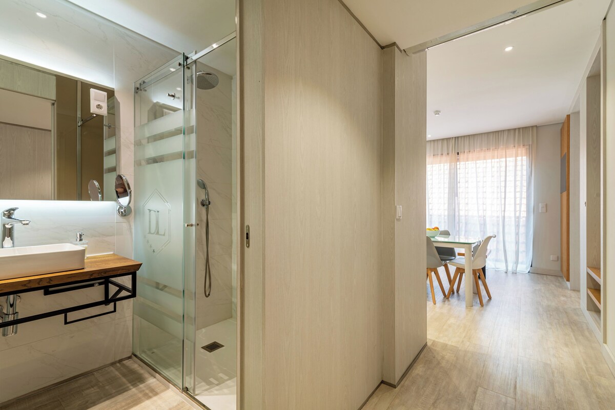 A modern bathroom with a glass shower enclosure, a wooden vanity, and a large mirror.