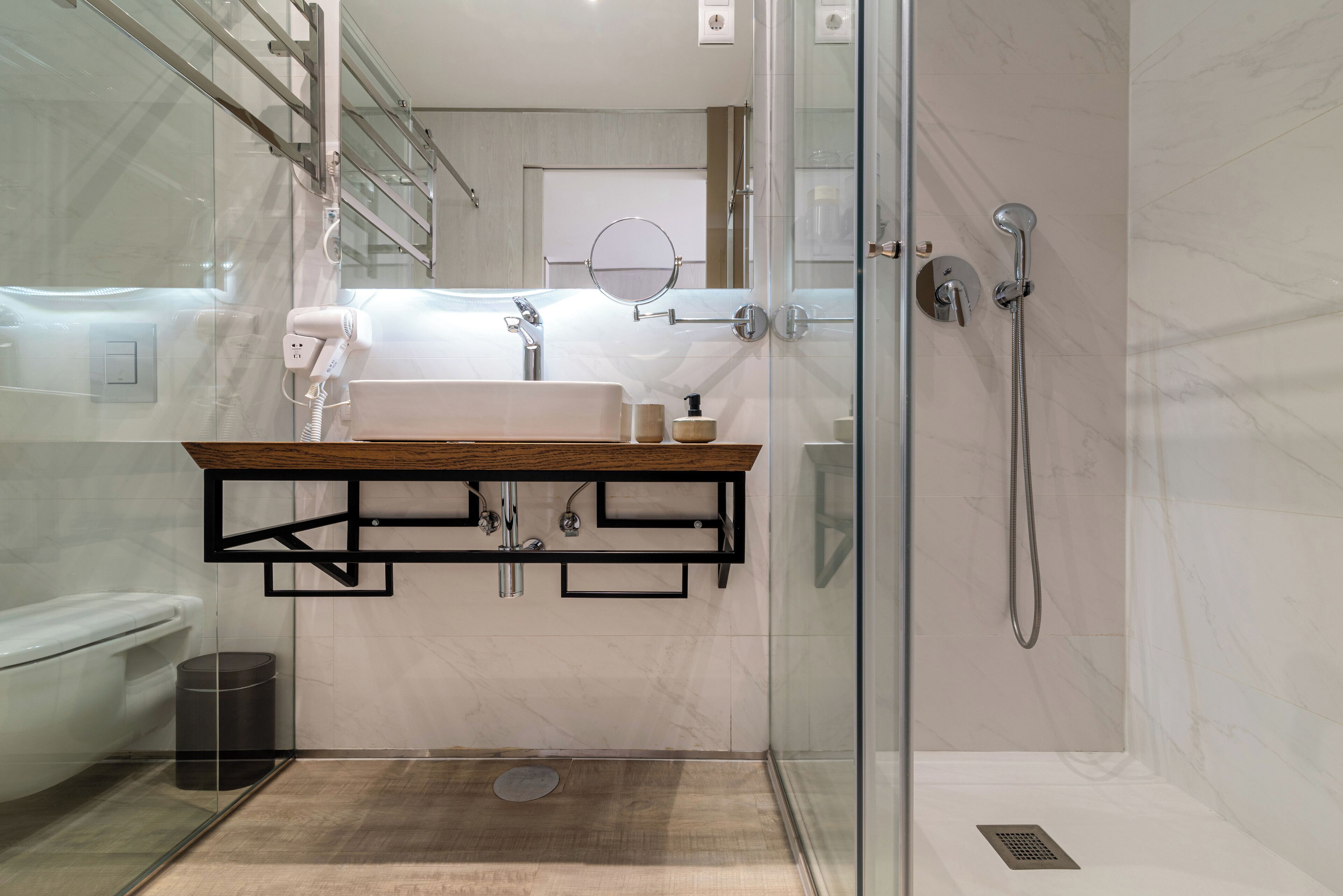 A modern bathroom with a glass shower enclosure, a wooden vanity, and a white toilet.