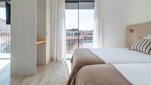 A modern hotel room with a large bed, a balcony with a city view, and a sliding glass door. - Smartr Porto Gaia & Spa (Vila Nova de Gaia)