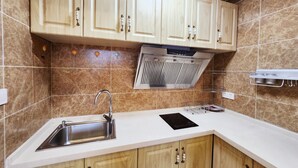 A kitchen with wooden cabinets, a stainless steel sink, a range hood, and a white countertop. - Zhu Youjia Homestay (Chongqing)