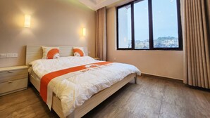 A hotel room with a large bed, a nightstand, a dresser, and a window with a city view. - Zhu Youjia Homestay (Chongqing)