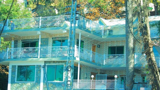 Un edificio de varios pisos con balcones, fachada de piedra y una escalera.