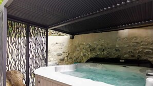 Un área de hidromasaje con pared de piedra y valla metálica.