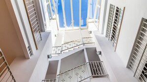 Een meerlaags interieur met trappen en leuningen, grote ramen en een uitzicht op het exterieur.