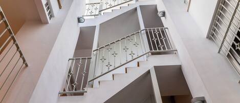A multi-level interior with staircases and railings, large windows, and a view of the outside.