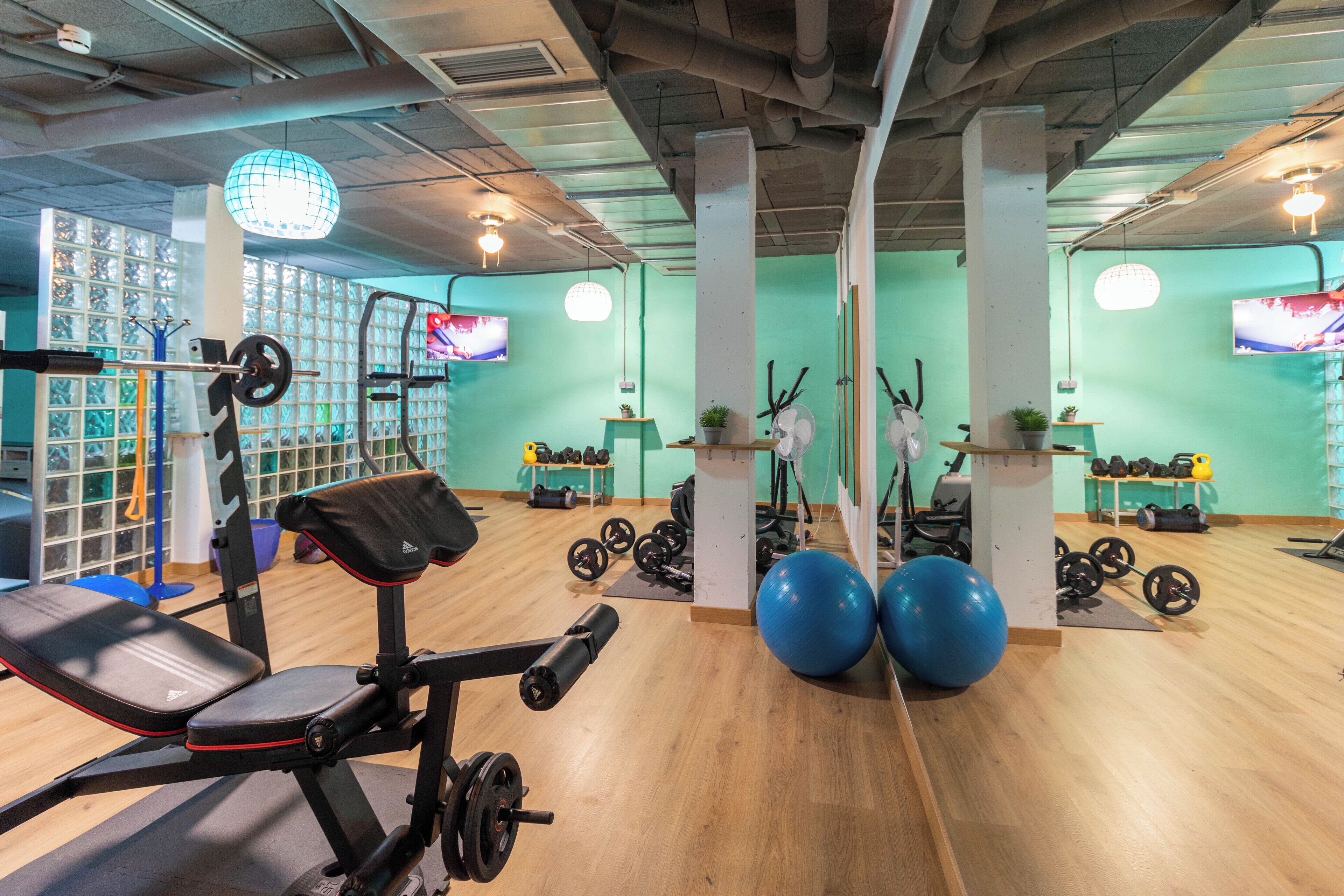 A gym with exercise equipment, a weight bench, and a large mirror.