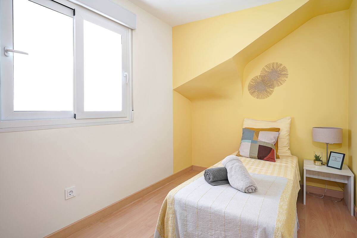 Une chambre à coucher avec un lit, une table de chevet, une lampe et une fenêtre.