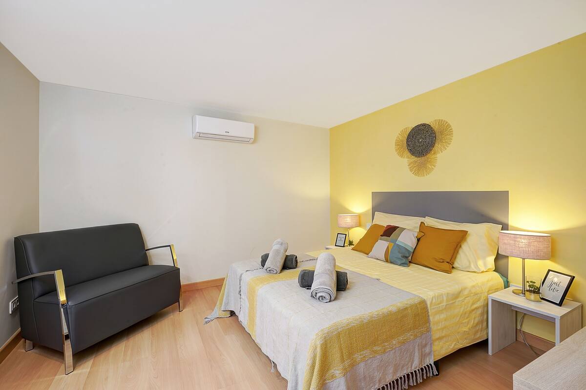 Une chambre d’hôtel équipée d’un lit, d’un canapé, d’une table de chevet et d’un appareil de climatisation.