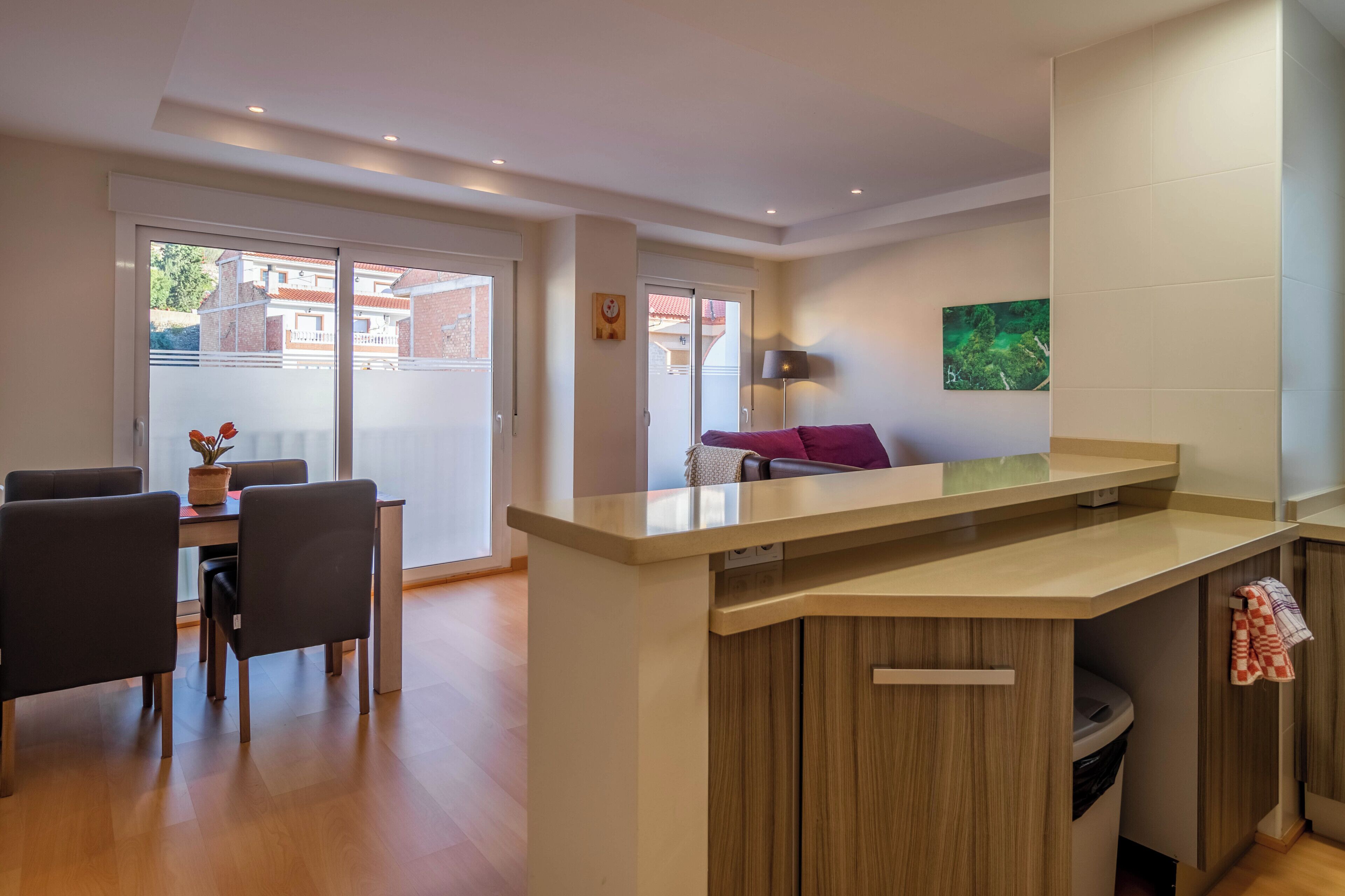 A modern kitchen with a central island, a dining area with chairs, and a sofa.