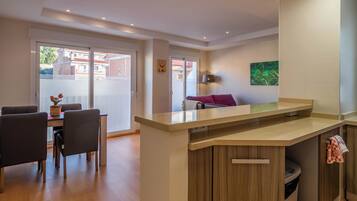 Una cocina moderna con una isla central, un comedor con sillas y un sofá.
