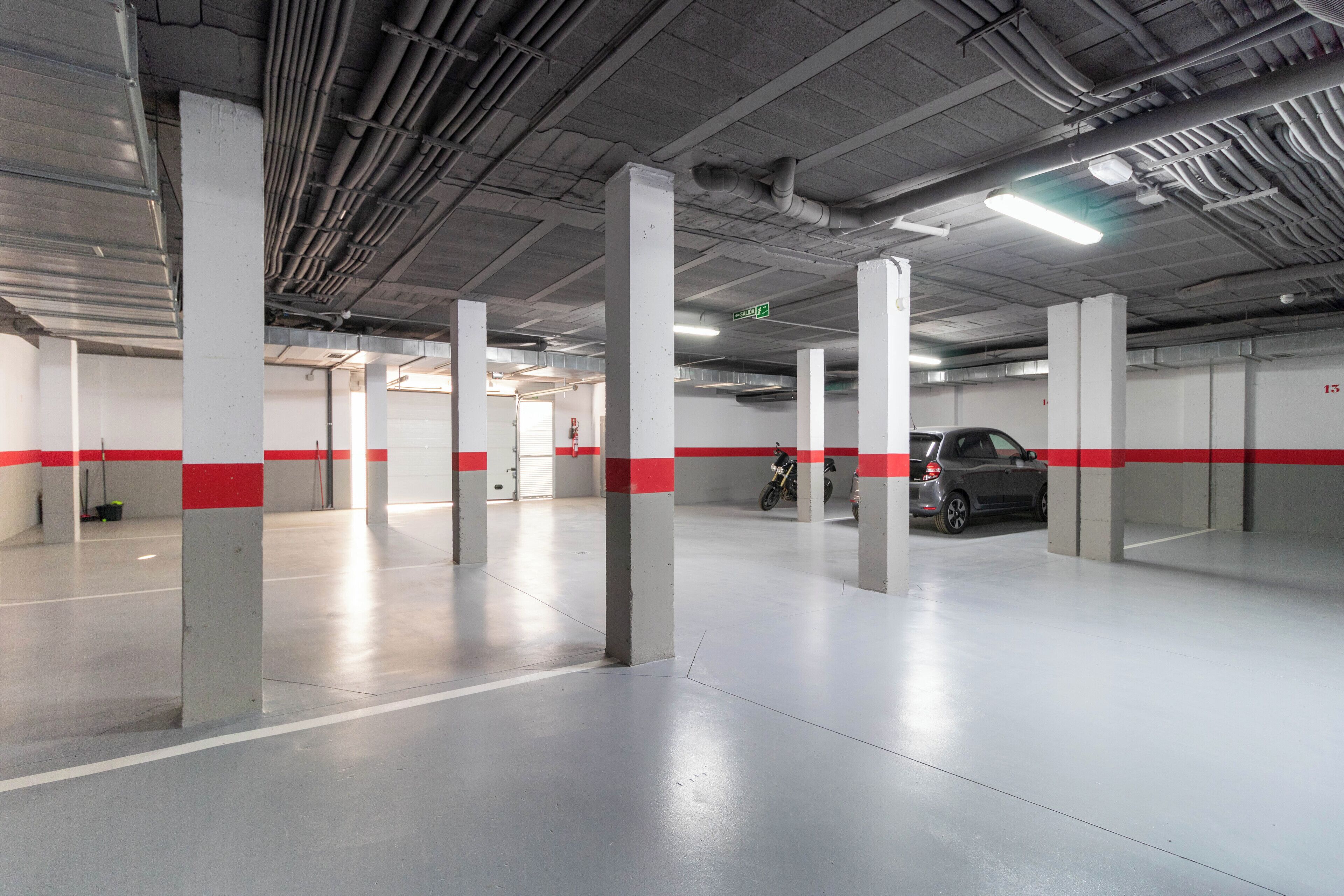 A multi-level parking garage with concrete pillars and red stripes, featuring a clean, industrial design.