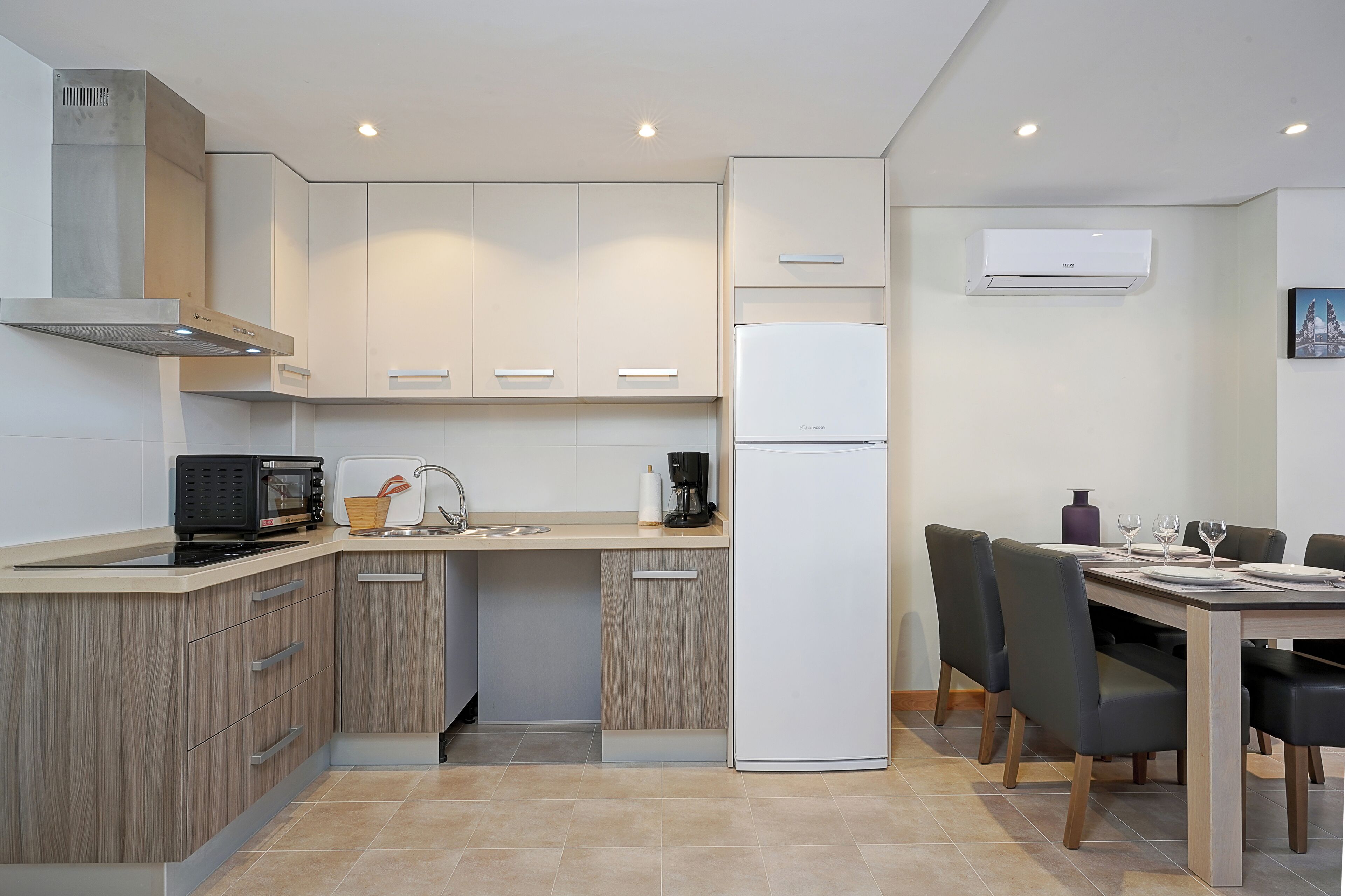 Una cocina moderna con armarios de madera, microondas integrado, cafetera y refrigerador.