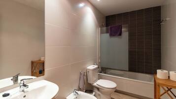Un baño moderno con lavamanos, bidé, inodoro y bañera.