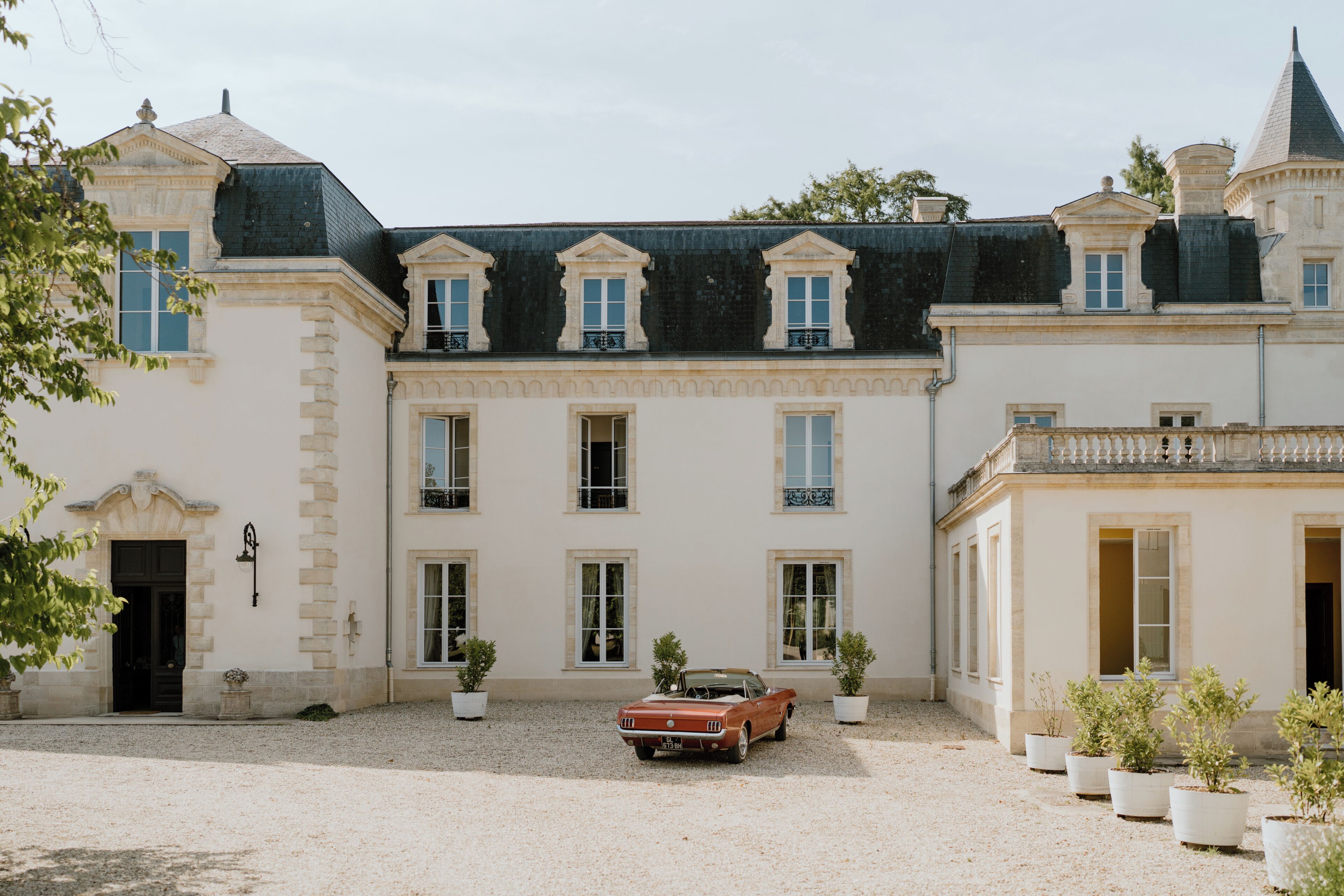 Un bâtiment historique doté d’une cour intérieure, d’une voiture ancienne et de plantes en pot.