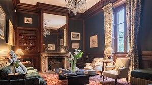 A traditional library room with a fireplace, bookshelves, and comfortable seating. - Château Sénéjac (Le Pian-Medoc)