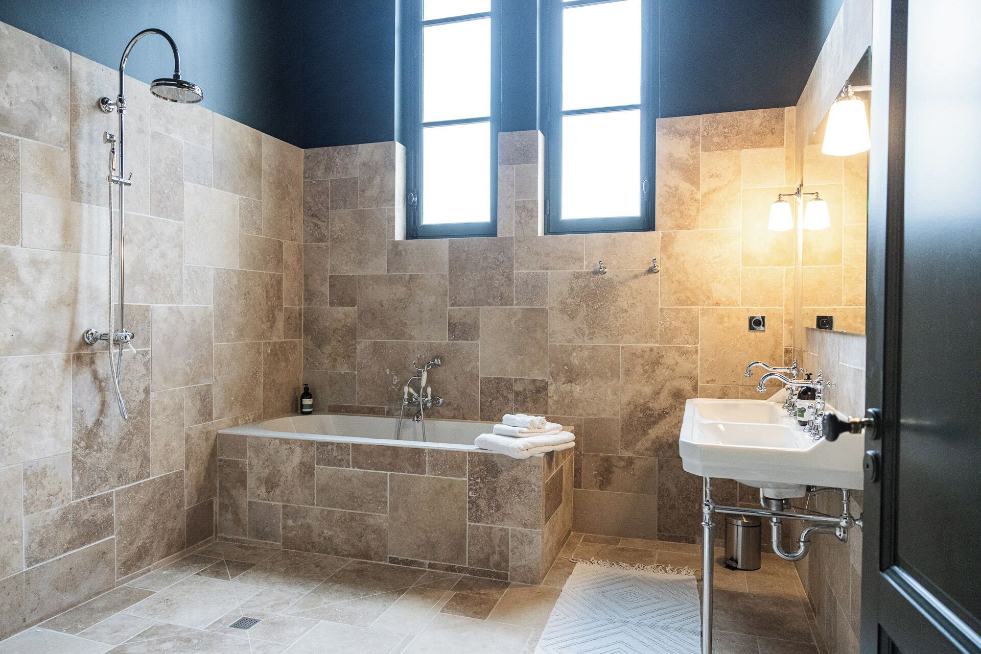 A modern bathroom with a freestanding bathtub, a showerhead, and a sink with a mirror.