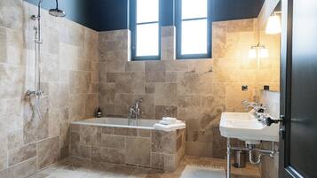A modern bathroom with a freestanding bathtub, a showerhead, and a sink with a mirror.