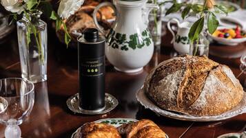 A dining table with a variety of food items, including bread, pastries, and a bottle of Domaine Saint Andreu wine.