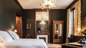 A classic room with a large bed, a fireplace, a mirror, and a chandelier. - Château Sénéjac (Le Pian-Medoc)