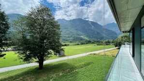 Ein Balkon mit Blick auf eine Berglandschaft, einen Baum und eine Straße.