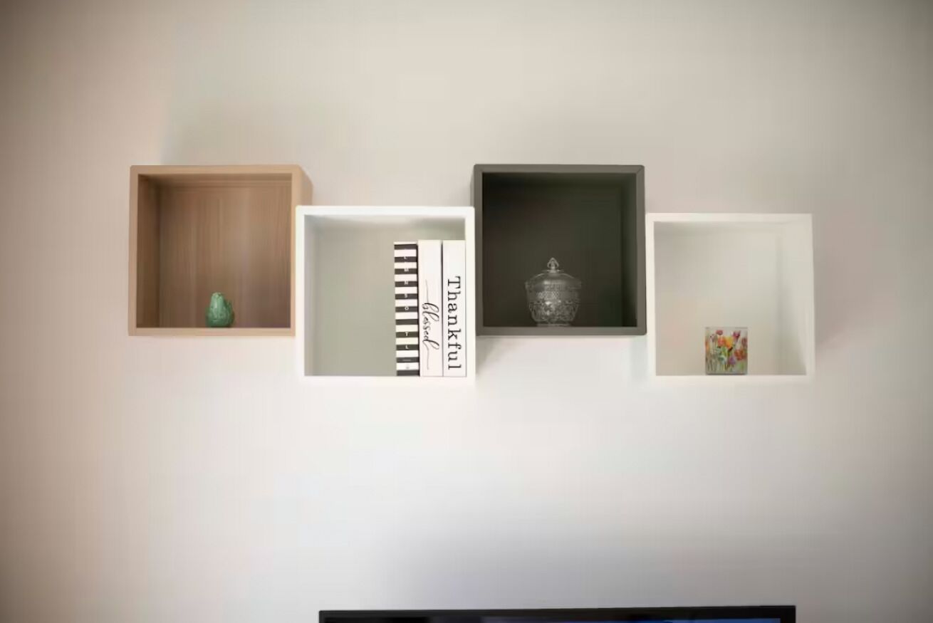 Una paret amb tres prestatges oberts que mostren diversos objectes decoratius.