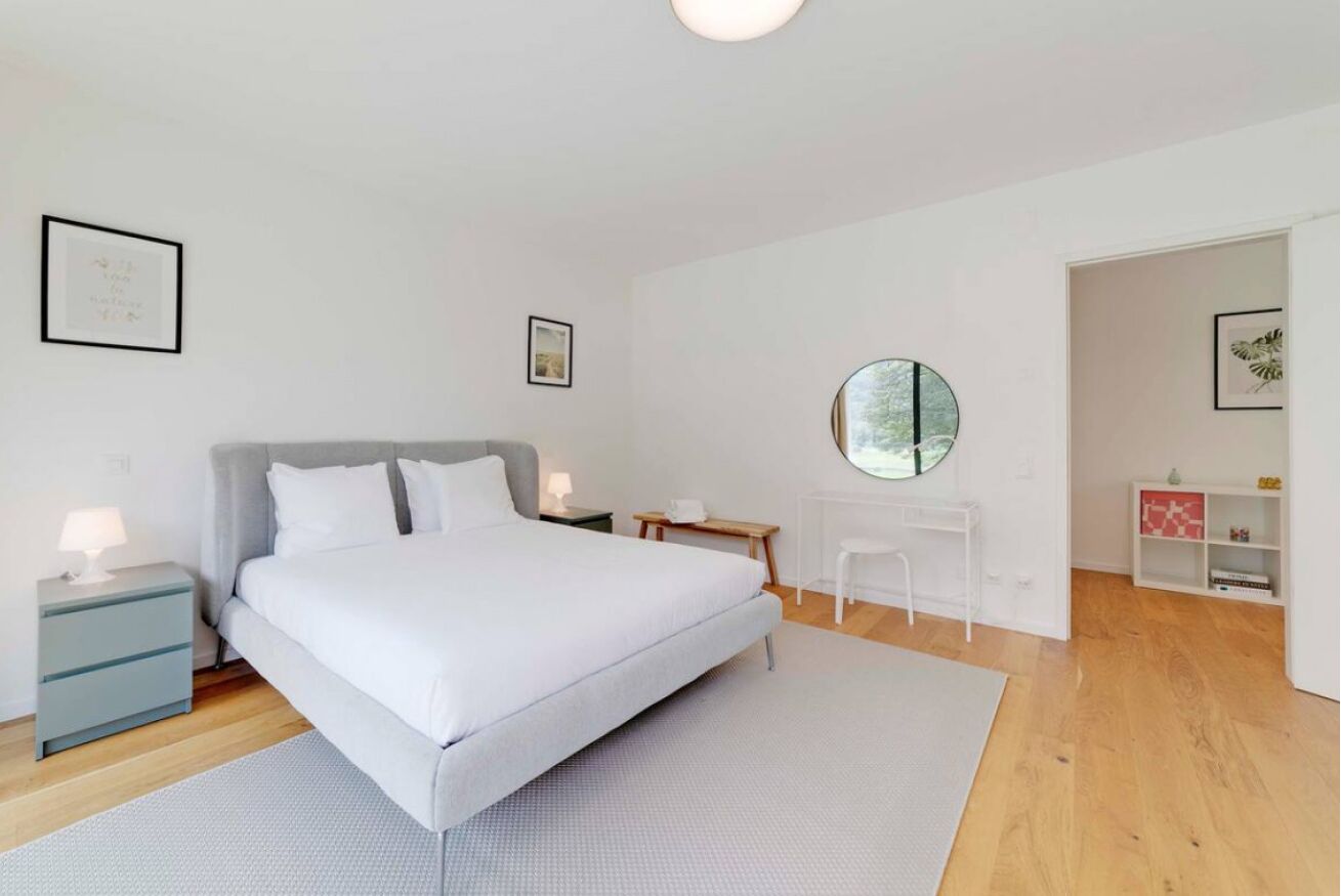 A modern bedroom with a large bed, bedside tables, a desk, and a mirror.